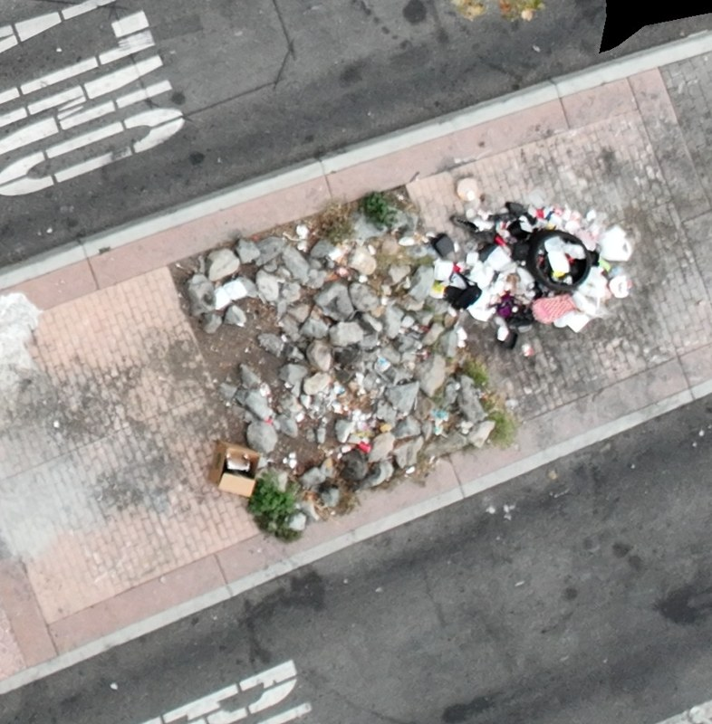 Dumped rubble and mixed waste on a paved traffic island