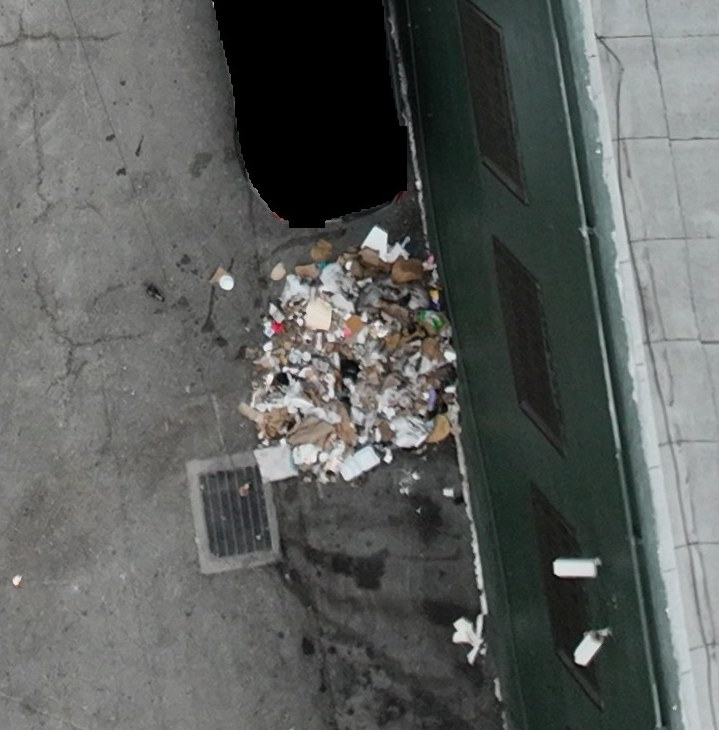 Loose waste piled against a building beside a storm drain