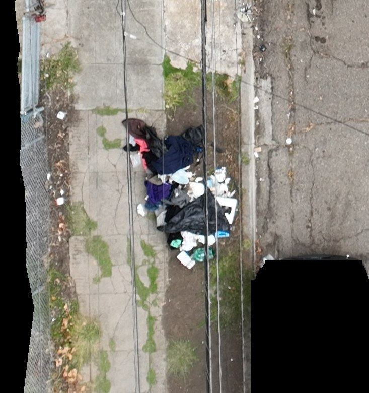 Discarded clothing, bags and other material along a sidewalk