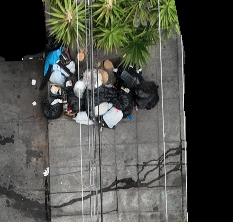 Bagged and loose waste on a sidewalk beneath overhead wires