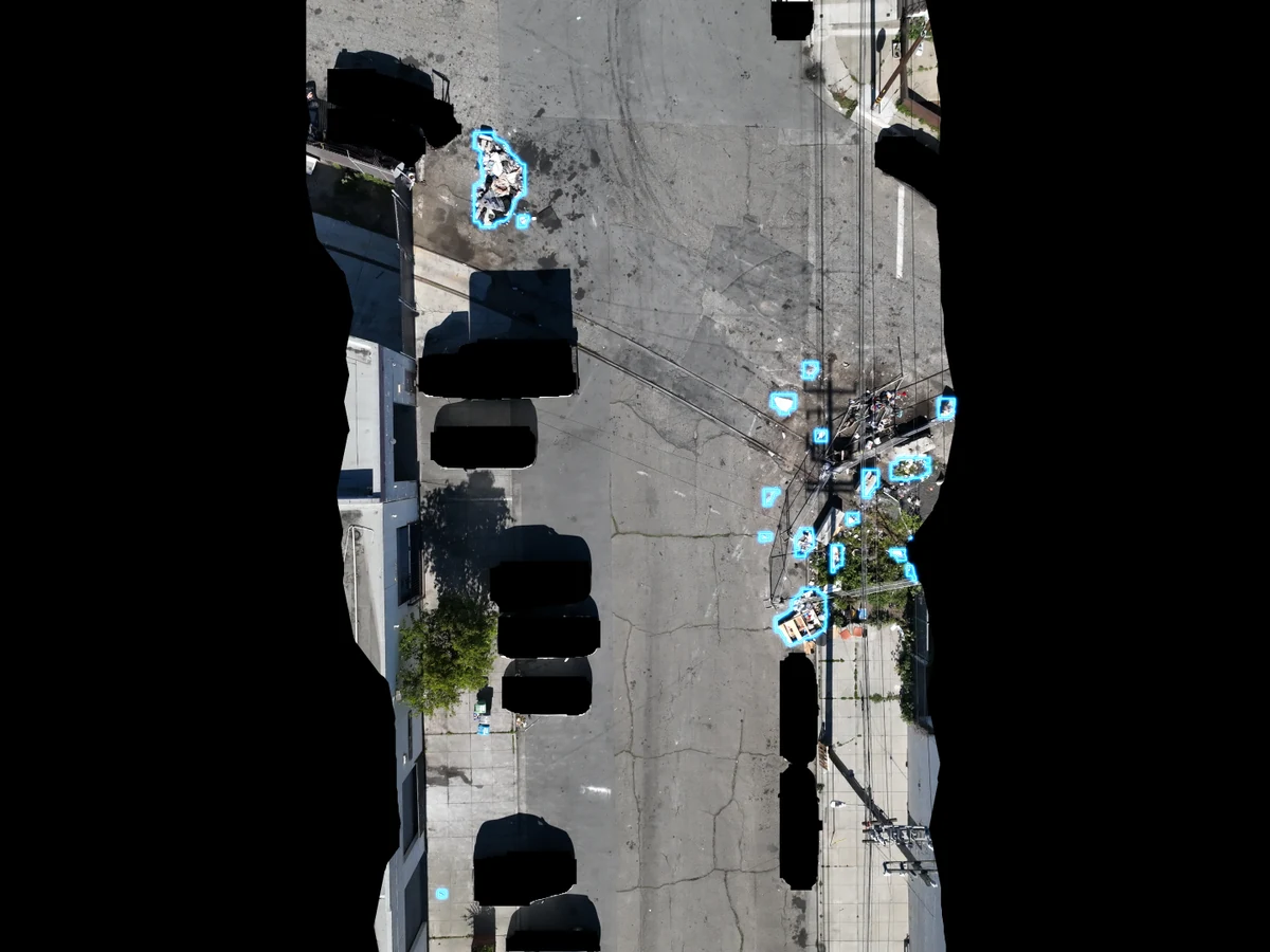 Aerial view of a street with cyan overlays marking large piles and scattered debris